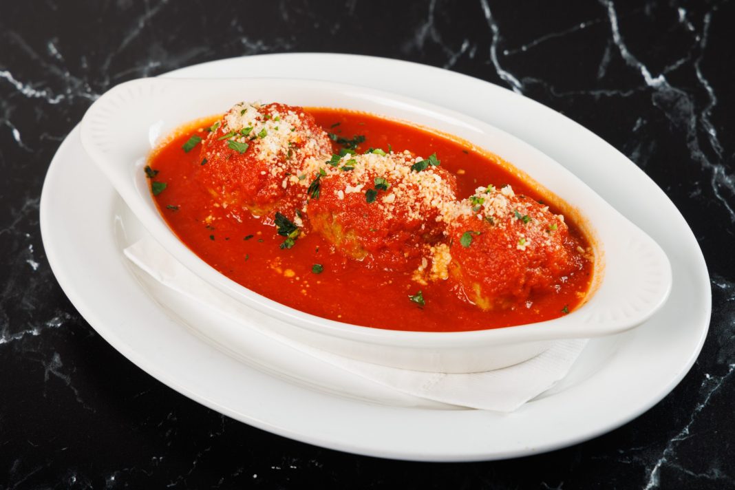 Sidedish with three meatballs, tomato sauce and parmesan cheese.