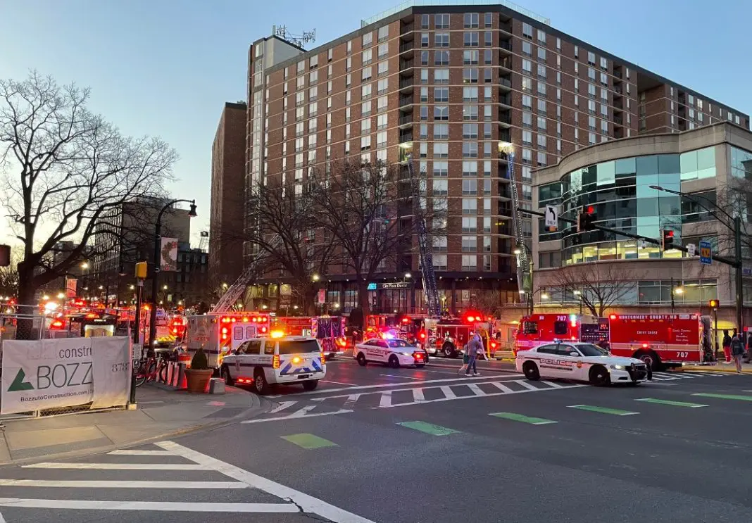 Fire trucks convene outside a large high-rise apartment building.