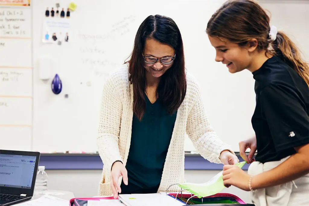 Teacher and child looking at a binder and smiling
